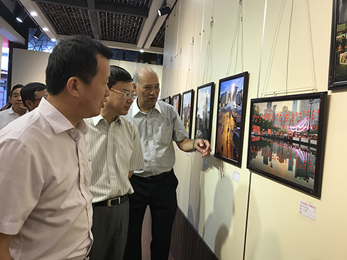 香港中華攝影學會副會長王貴光(右)向福建省僑聯主席陳式海(左)及福建省僑辦副主任林澤春(中)介紹展出的作品。