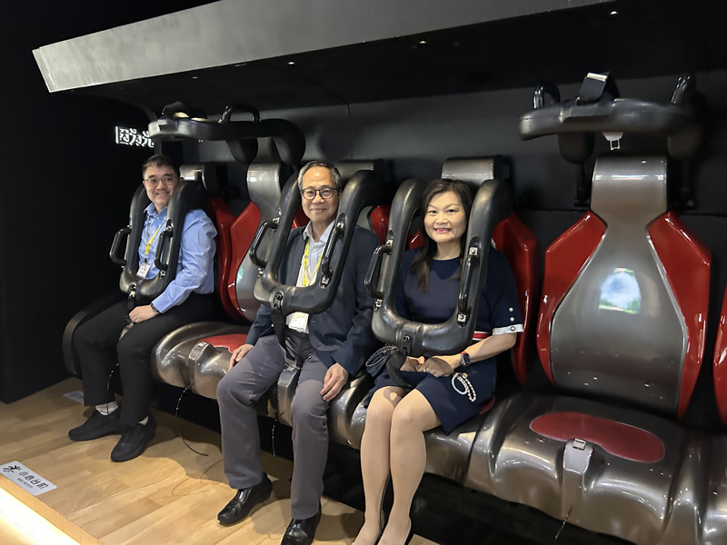 黎瑞琼主任（右一）、工業總會副主席岑健偉（右二）和考察團成員在光明區城市規劃展覽館展廳，觀看利用5D技術介紹光明區規劃全貌的視頻